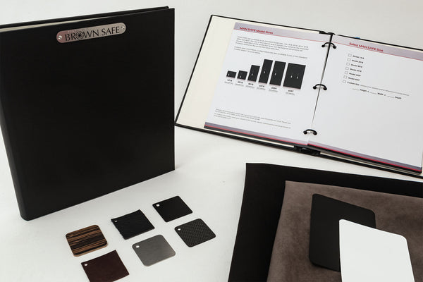 A display of items included in the Man Safe Design Kit, such as a design booklet, exterior paint color samples, interior finish samples, and specification sheets.